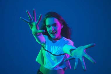 Beyaz kadın portresi mavi stüdyo arka planında izole edilmiş pembe-yeşil neon ışıklı, şık ve güzel