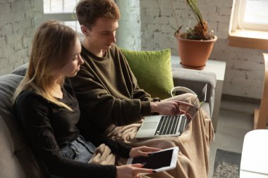 Çekici genç çift birlikte cihazlar kullanıyor, tablet, laptop, akıllı telefon, kablosuz kulaklık. Tüm dünyadaki insanları birbirine bağlayan araçlar ve teknolojiler