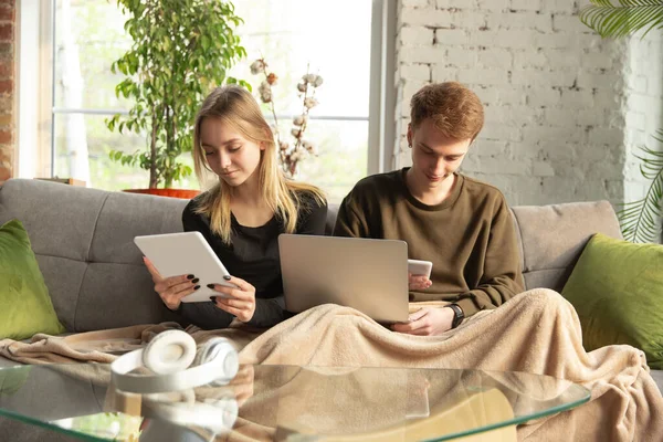 Atractiva pareja joven que utiliza dispositivos juntos, tableta, ordenador portátil, teléfono inteligente, auriculares inalámbricos. Gadgets y tecnologías que conectan a personas de todo el mundo — Foto de Stock