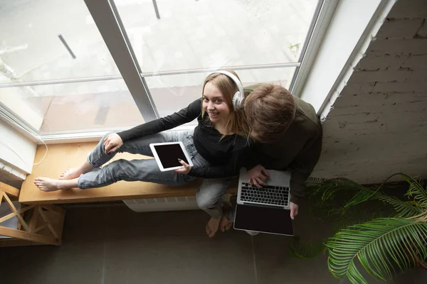 Casal jovem atraente usando dispositivos juntos, tablet, laptop, smartphone, fones de ouvido sem fio. Gadgets e tecnologias conectando pessoas em todo o mundo. Vista superior — Fotografia de Stock