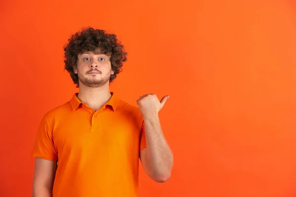 Blanke jonge mannen monochrome portret op oranje studio achtergrond — Stockfoto