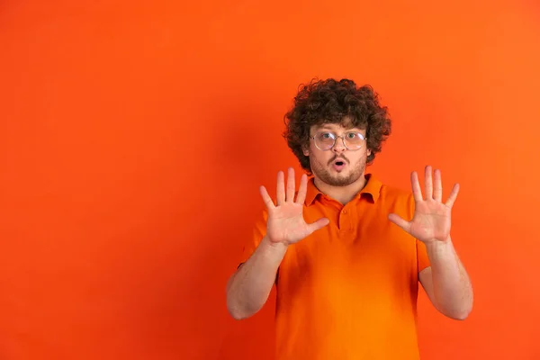 Blanke jonge mannen monochrome portret op oranje studio achtergrond — Stockfoto