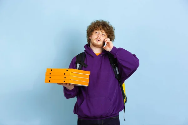 Servizio di consegna senza contatto durante la quarantena. L'uomo consegna cibo e borse della spesa durante l'isolamento. Emozioni del fattorino isolato su sfondo blu . — Foto Stock