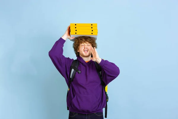 Servizio di consegna senza contatto durante la quarantena. L'uomo consegna cibo e borse della spesa durante l'isolamento. Emozioni del fattorino isolato su sfondo blu . — Foto Stock