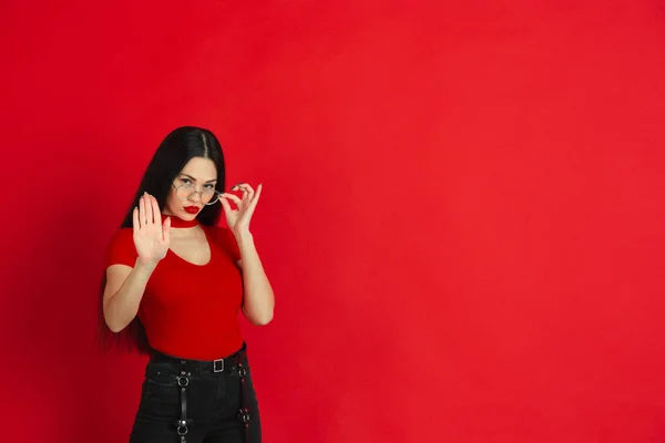 Wanita muda kaukasia potret monokrom pada latar belakang studio merah, emosional dan ekspresif — Stok Foto