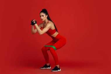 Kırmızı stüdyo arka planında pratik yapan güzel genç bayan sporcu, tek renkli portre.