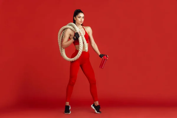 Piękna młoda atletka ćwicząca na czerwonym tle studia, monochromatyczny portret — Zdjęcie stockowe