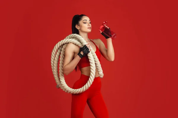 Mooie jonge vrouwelijke atleet oefenen op rode studio achtergrond, monochrome portret — Stockfoto