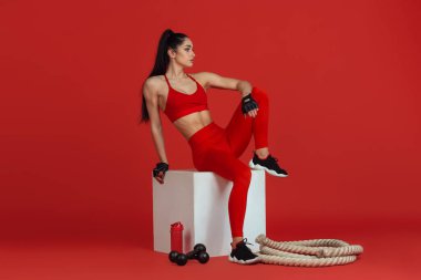 Kırmızı stüdyo arka planında pratik yapan güzel genç bayan sporcu, tek renkli portre.