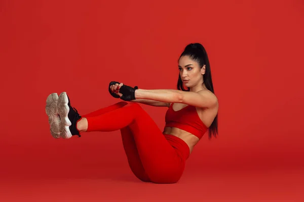 Bonita jovem atleta praticando no fundo estúdio vermelho, retrato monocromático — Fotografia de Stock