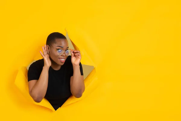 Jovem alegre posa em rasgado papel amarelo buraco fundo, emocional e expressivo — Fotografia de Stock