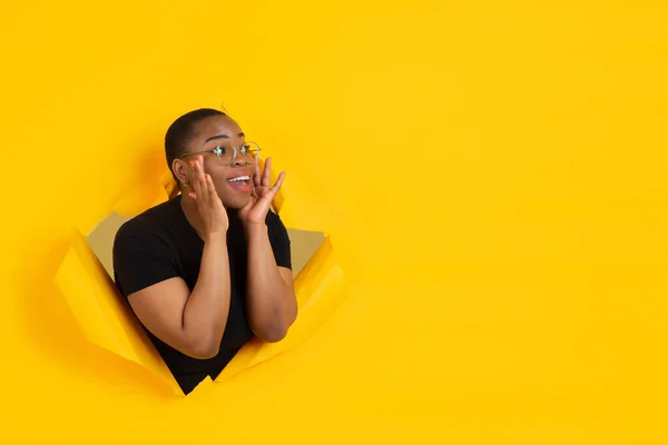 Veselá mladá žena pózuje v roztrhaném žlutém papírovém pozadí, emocionální a expresivní, křičí s mluvčím — Stock fotografie