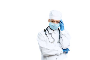 Stetoskop ve yüz maskesi olan genç bayan doktor beyaz stüdyo arka planında izole edilmiş.