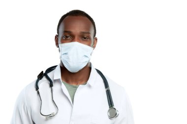 Steteskop ve yüz maskesi olan genç bir erkek doktor beyaz stüdyo arka planında izole edilmiş.