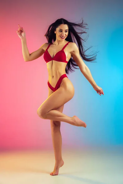 Modeporträt einer jungen, fitten und sportlichen Frau in stilvoller roter Luxus-Badebekleidung auf Steigungsuntergrund. Perfekter Körper bereit für den Sommer. — Stockfoto