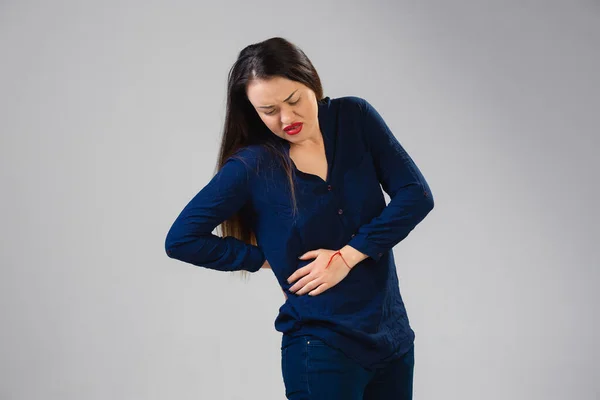 Mulher jovem sofre de dor, sente-se doente, doente e fraqueza isoladas no fundo do estúdio — Fotografia de Stock