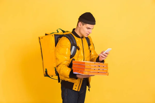 Bezkontaktní doručení během karantény. Muž doručuje jídlo a nákupní tašky během izolace. Emoce doručovatele izolované na žlutém pozadí. — Stock fotografie