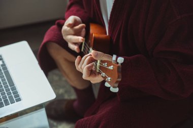 Karantina sırasındaki olgun yaşlı adam, virüs salgını, online gitar çalma dersleri verme, ellerinizi kapatın.
