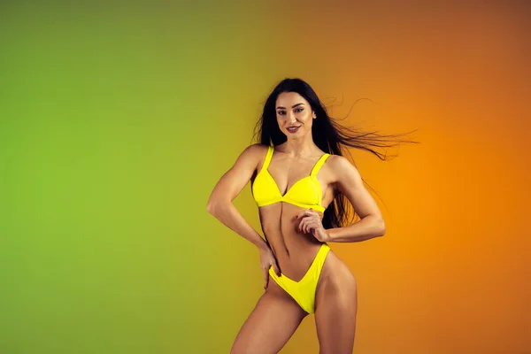 Retrato de moda de jovem em forma e mulher esportiva em trajes de banho elegantes de luxo amarelo no fundo gradiente. Corpo perfeito pronto para o verão . — Fotografia de Stock