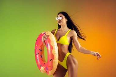 Genç fit ve sportif kadının şık sarı mayo giymiş kauçuk donatıyla moda portresi. Yaz için mükemmel vücut hazır..