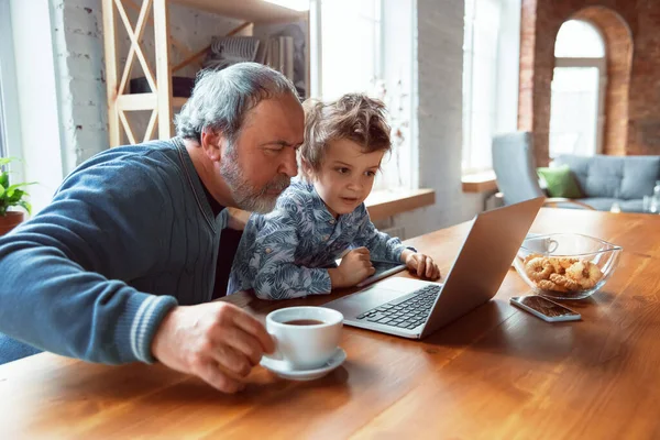 Grandfather and his grandson spending time insulated at home, stadying, watching cinema, shopping together — Stock Photo, Image