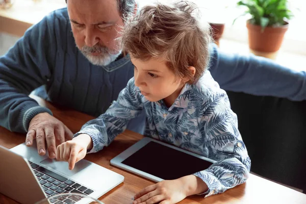 Grandfather and his grandson spending time insulated at home, stadying, watching cinema, shopping together