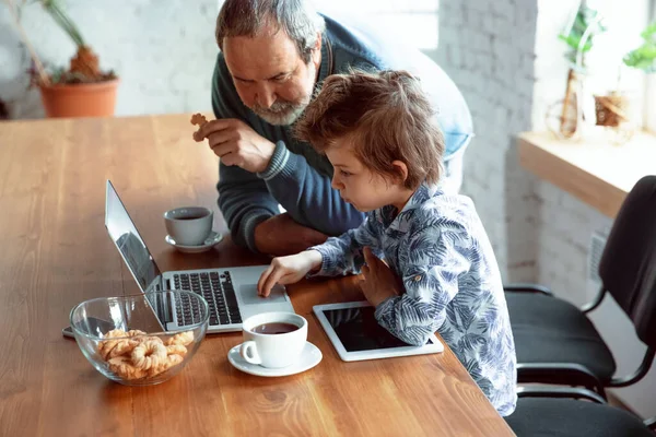 Grandfather and his grandson spending time insulated at home, stadying, watching cinema, shopping together