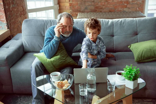 Дідусь і його онук проводять час утеплений вдома, заїкаючись, дивлячись кіно, купуючи разом — стокове фото