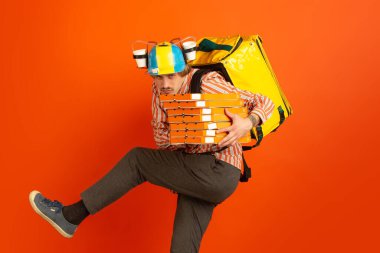 Karantina sırasında irtibatsız teslimat servisi. İnsan izolasyon sırasında yiyecek ve alışveriş torbaları dağıtır. Teslimatçının duyguları turuncu arka planda izole edilmiş..