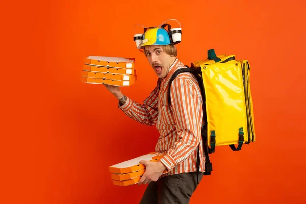 Servizio di consegna senza contatto durante la quarantena. L'uomo consegna cibo e borse della spesa durante l'isolamento. Emozioni di fattorino isolato su sfondo arancione . — Foto Stock