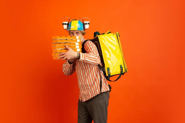 Bezdotykowa dostawa podczas kwarantanny. Człowiek dostarcza żywność i torby na zakupy podczas izolacji. Emocje doręczyciela na pomarańczowym tle. — Zdjęcie stockowe