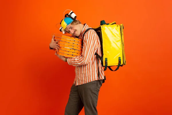 Serviço de entrega sem contato durante a quarentena. O homem entrega comida e sacos de compras durante o isolamento. Emoções de entregador isolado em fundo laranja . — Fotografia de Stock