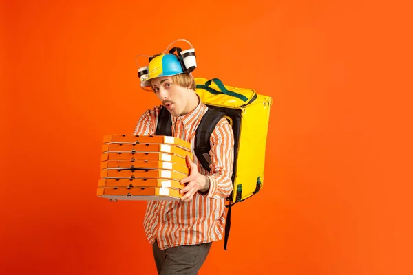 Service de livraison sans contact pendant la quarantaine. Homme livre de la nourriture et des sacs à provisions pendant l'isolation. Émotions du livreur isolé sur fond orange . — Photo