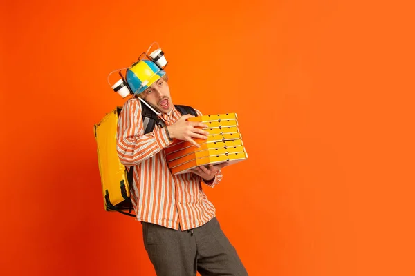 Serviço de entrega sem contato durante a quarentena. O homem entrega comida e sacos de compras durante o isolamento. Emoções de entregador isolado em fundo laranja . — Fotografia de Stock