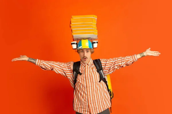 Servicio de entrega sin contacto durante la cuarentena. El hombre entrega comida y bolsas de la compra durante el aislamiento. Emociones del repartidor aisladas sobre fondo naranja . — Foto de Stock