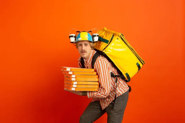 Service de livraison sans contact pendant la quarantaine. Homme livre de la nourriture et des sacs à provisions pendant l'isolation. Émotions du livreur isolé sur fond orange . — Photo