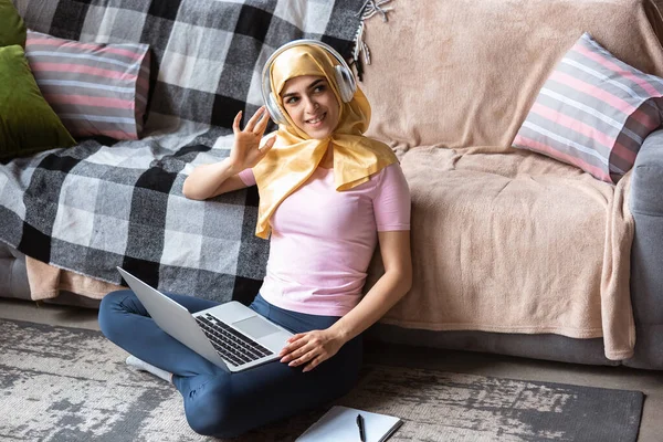 Una bella giovane donna musulmana a casa durante la quarantena e l'autoisolamento, usando il computer portatile, ascoltare musica, guardare cinema, periodici, shopping, studiare. — Foto Stock