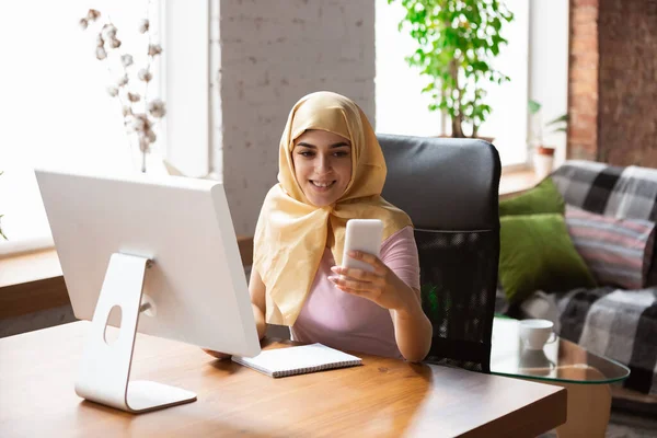 Una bella giovane donna musulmana a casa durante la quarantena e l'autoisolamento, il lavoro a distanza, lo shopping, lo studio, guardare il cinema — Foto Stock