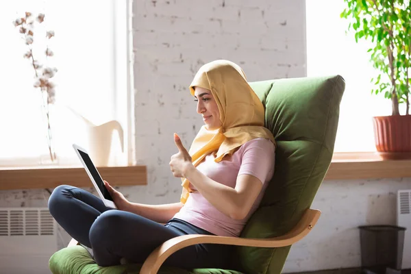 Ładna młoda muzułmanka w domu podczas kwarantanny i samoizolacji, korzystająca z laptopa do wideokonferencji, oglądająca kino, seriale, zakupy, studia — Zdjęcie stockowe