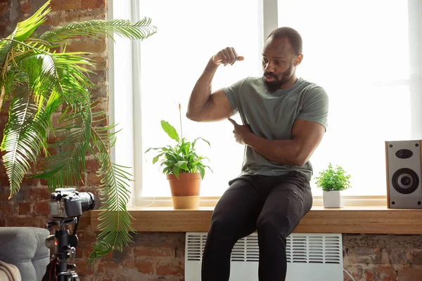 Junger afrikanisch-amerikanischer Mann unterrichtet zu Hause Online-Kurse für Fitness, Aerobic, sportlichen Lebensstil während der Quarantäne, Aufzeichnung vor der Kamera, Streaming — Stockfoto