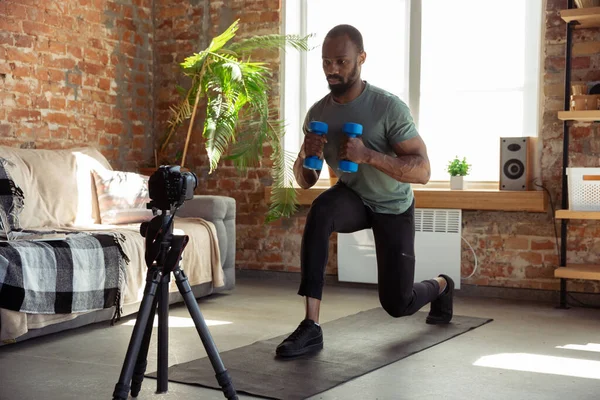 Jonge Afrikaans-Amerikaanse man die thuis les geeft in online fitnesscursussen, aerobic, sportieve levensstijl tijdens quarantaine, opnieuw opnemen op camera, streamen — Stockfoto