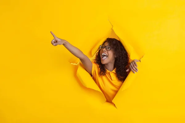 Joven alegre posa en el fondo del agujero de papel amarillo rasgado, emocional y expresivo — Foto de Stock