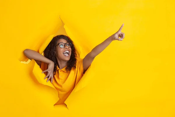 Jovem alegre posa em rasgado papel amarelo buraco fundo, emocional e expressivo — Fotografia de Stock