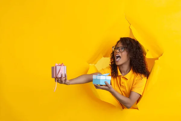 Vrolijke jonge vrouw poseert in gescheurd geel papier gat achtergrond, emotioneel en expressief — Stockfoto