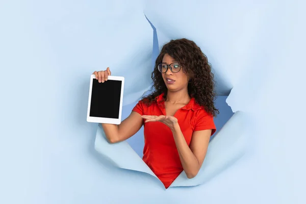 Joyeux jeune femme pose dans fond de trou de papier bleu déchiré, émotionnel et expressif — Photo