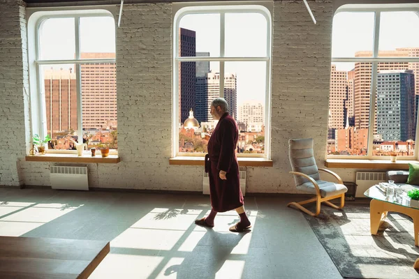 Mature senior older man during quarantine, realizing how important stay at home during virus outbreak, looking throught window on day Boston city — Stock Photo, Image