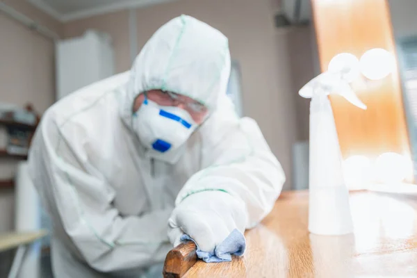 Koronavirová pandemie. Dezinfekce v ochranném obleku a masce rozstřikuje dezinfekční prostředky v domě nebo kanceláři — Stock fotografie