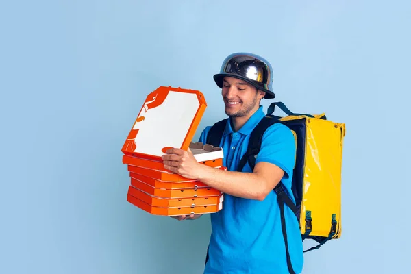 Serviço de entrega sem contato durante a quarentena. O homem entrega comida e sacos de compras durante o isolamento. Emoções de entregador isolado em fundo azul . — Fotografia de Stock