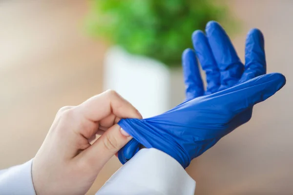 Primer plano de las manos de los médicos con guantes protectores azules sobre fondo de mesa de madera — Foto de Stock