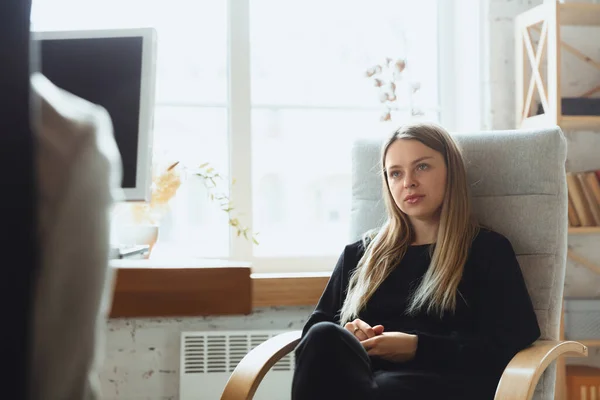 Young woman sitting in office during the job interview with female employee, boss or HR-manager, talking, thinking, looks confident — Stock Photo, Image